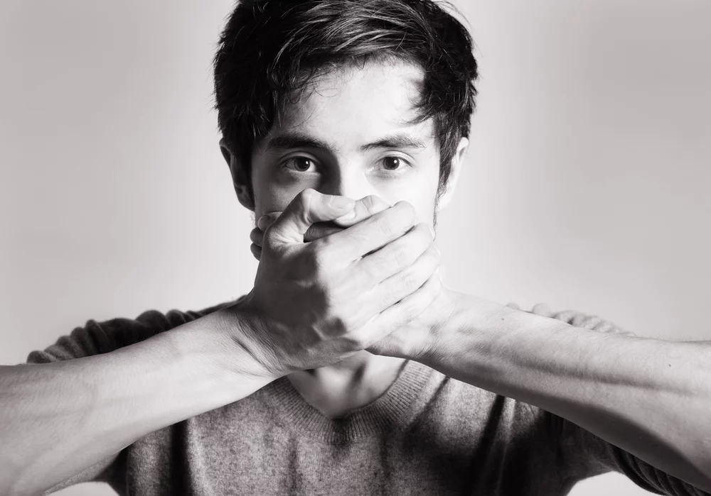 Man covering his mouth to stop himself from saying something that's incorrect or inappropriate