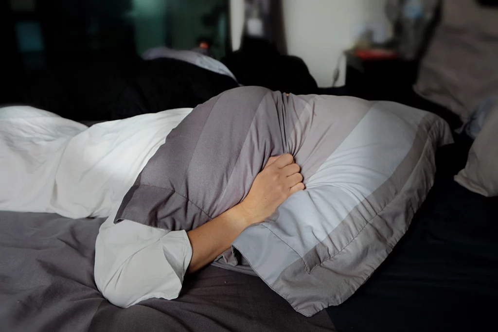 woman with head under pillow